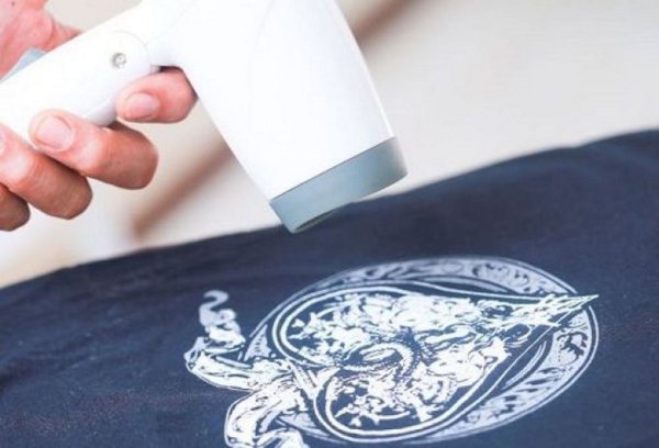 Клеит наклейку на одежду