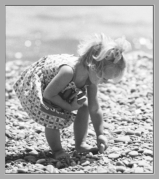 Девочка собирает гальку на море
