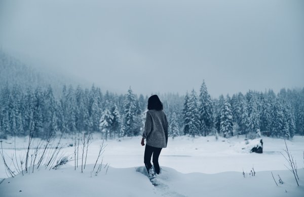 Девушка в зимнем лесу со спины