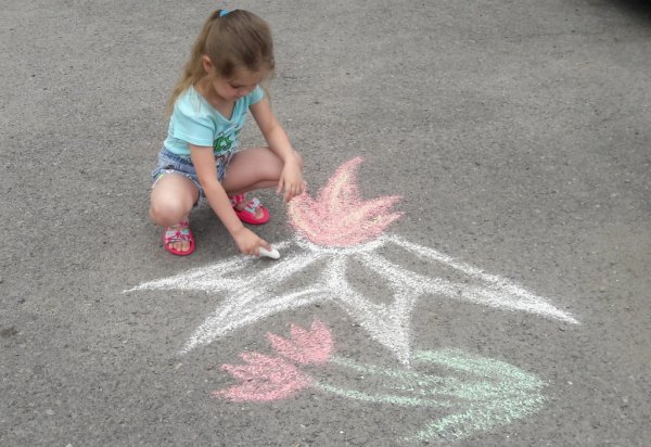 Девочка рисует на асфальте